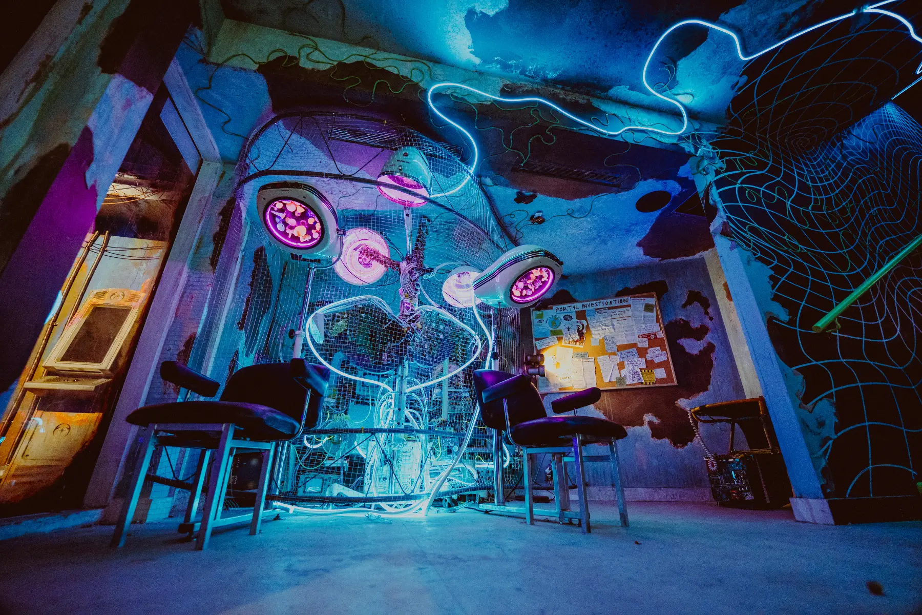 An Absurd City room with blue and purple lighting, sculptural equipment and immersive set details.